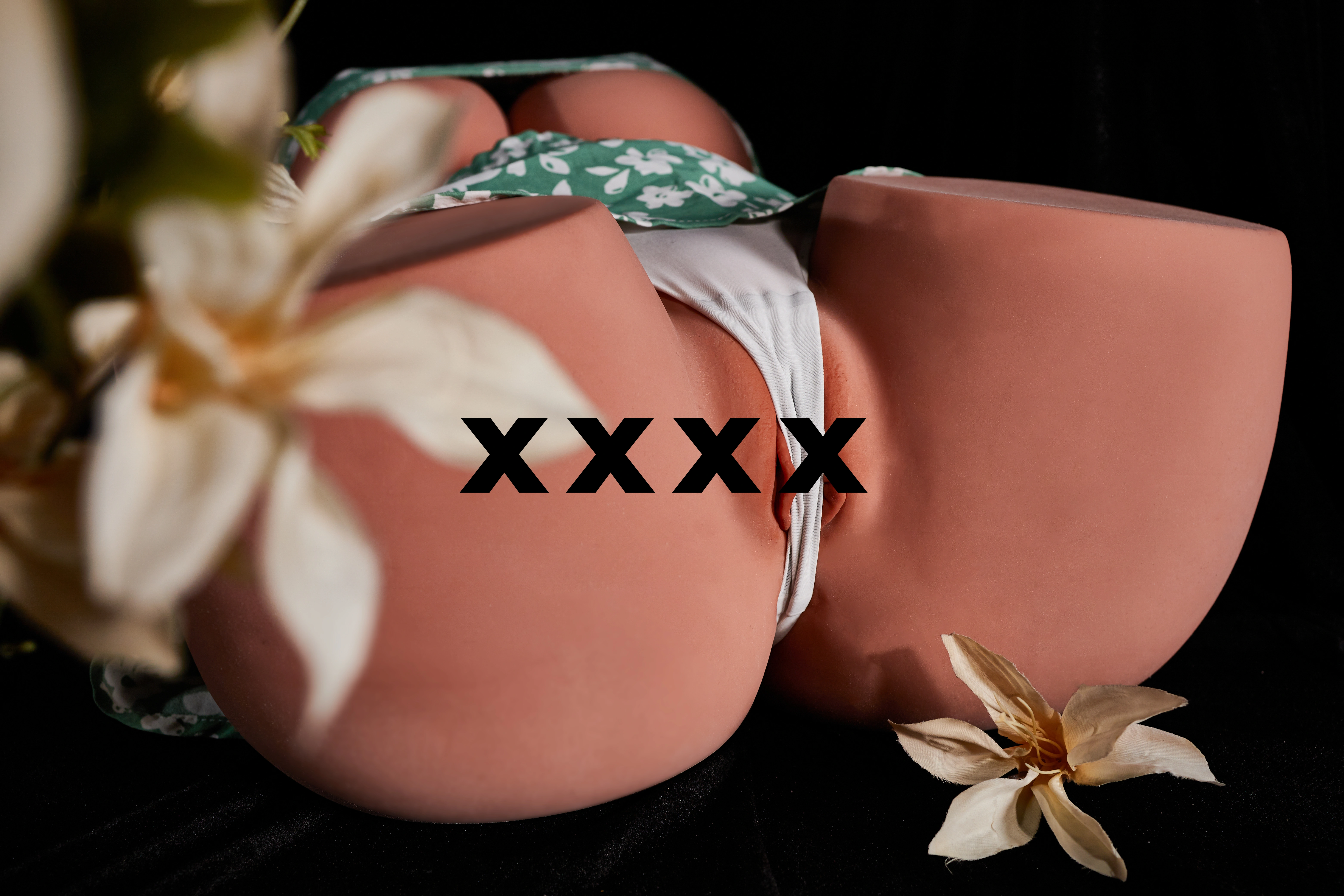 一件绿色花纹衣物和白色内裤展示在黑色背景上，旁边有白色花朵装饰。