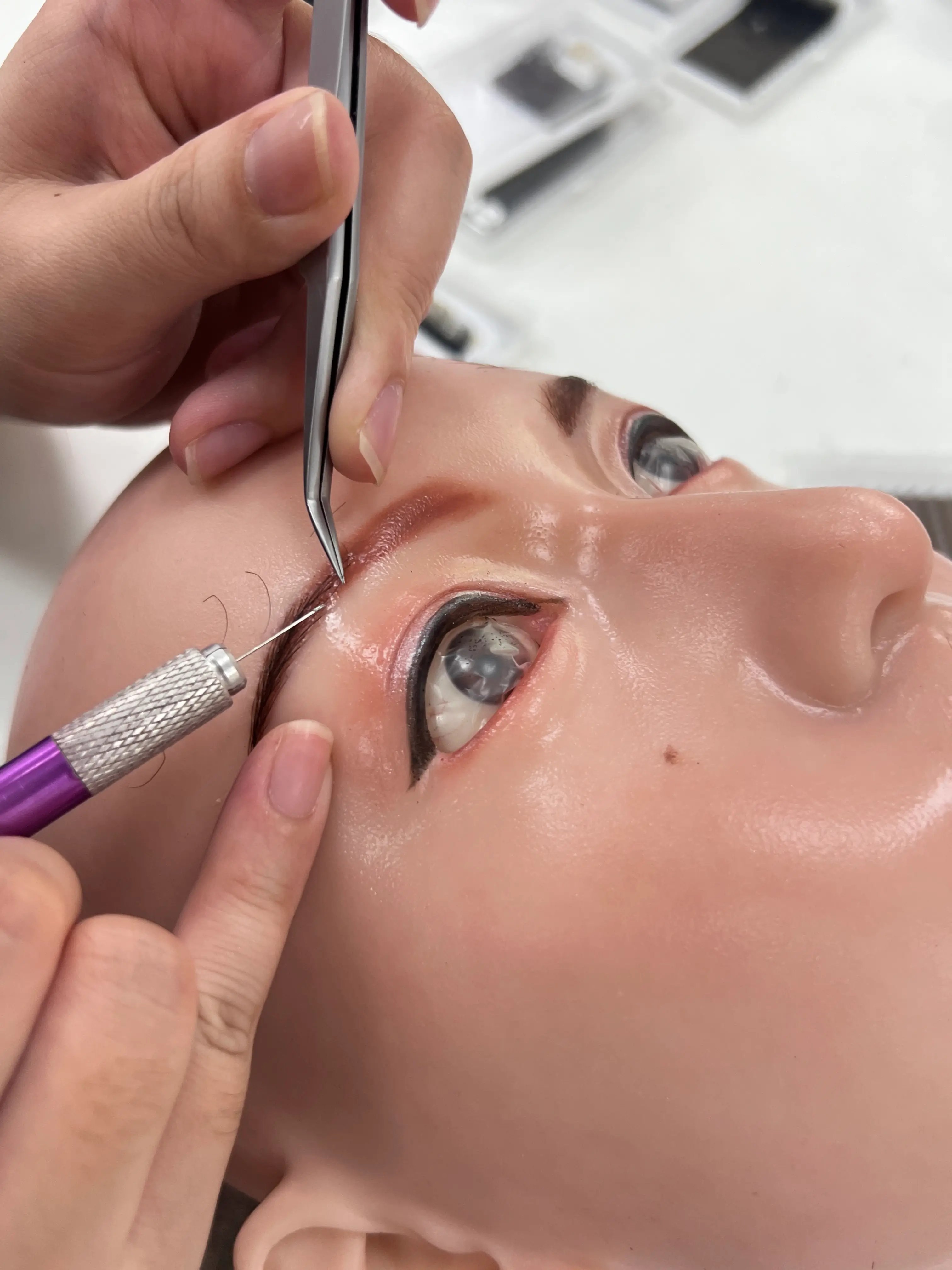 Hand-applied eyebrow and facial detailing on an artificial doll head
